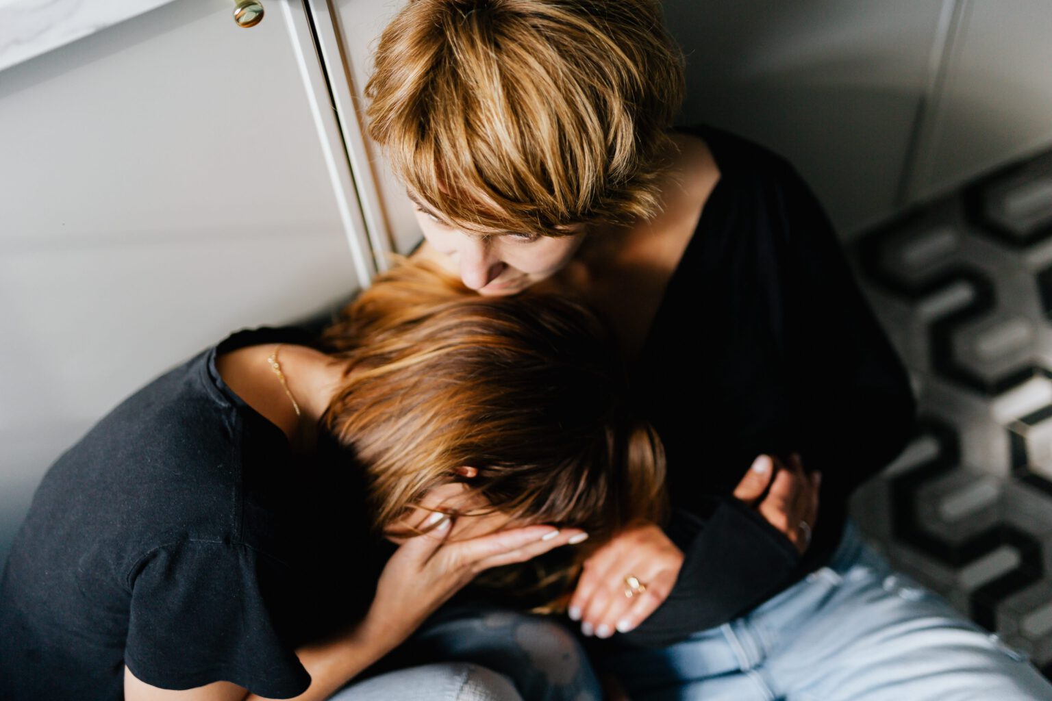 Woman in head in hands. Another woman with chin on the others head