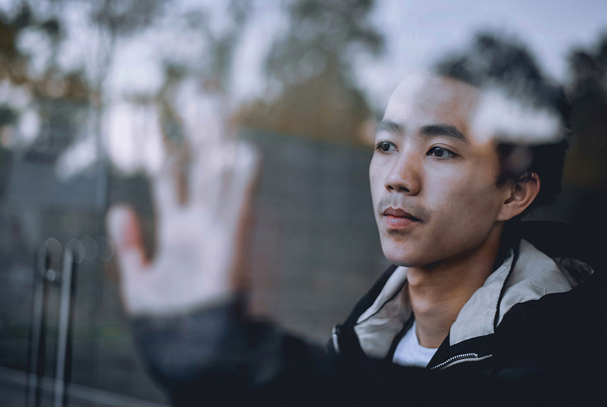 Man with hand on glass looking out window