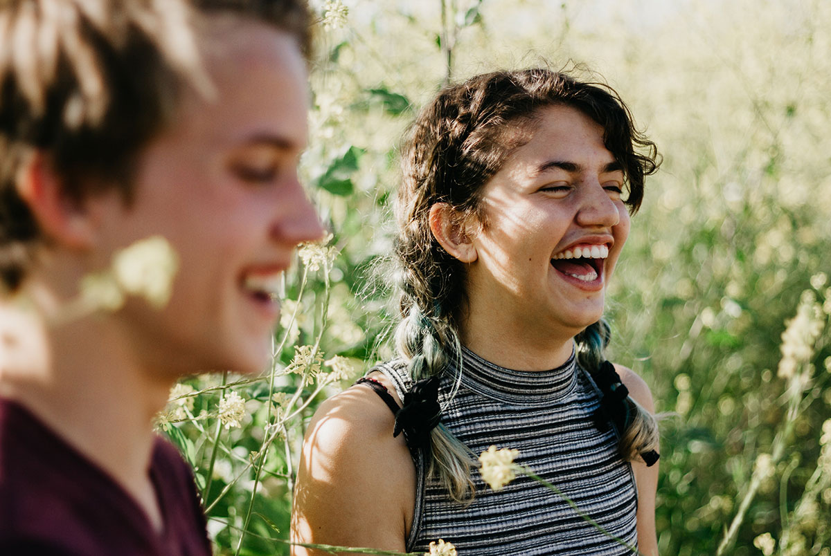 Boy and girls laughing and smiling in a field of flowers