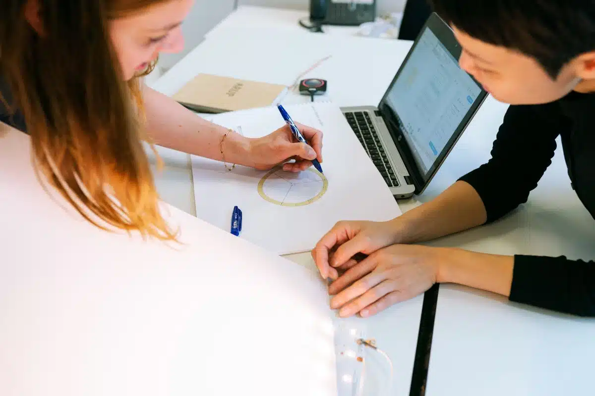 Two women leaning over desk working