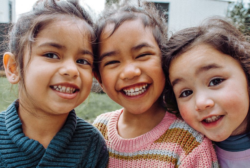 Three young girls smiling towards camera.