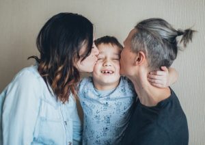 Parents kissing son.