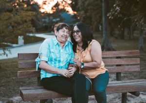 Elderly women laughing on a bench together.