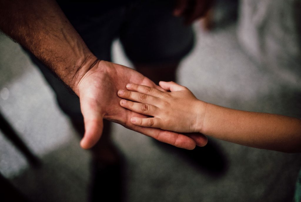 A child's hand placed in the palm of an outstretched adult's hand.