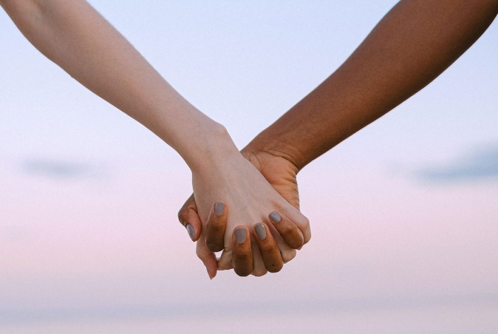 Two people holding hands with a pink sky in the background.