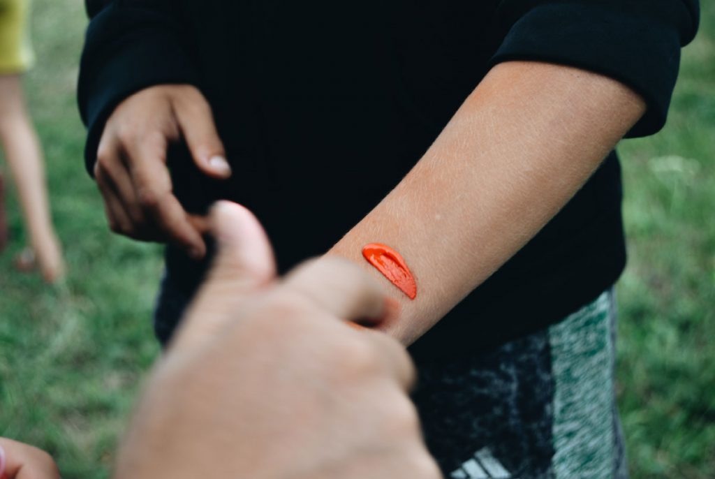 A person applying orange paint to another person's forearm.
