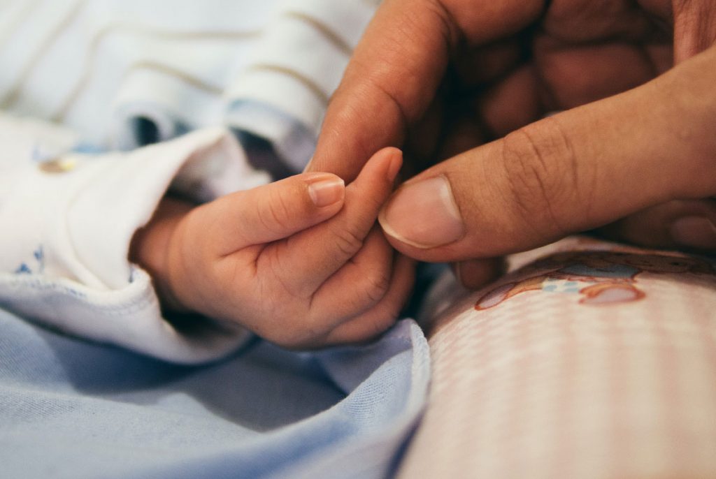 An adult holding a baby's hand.