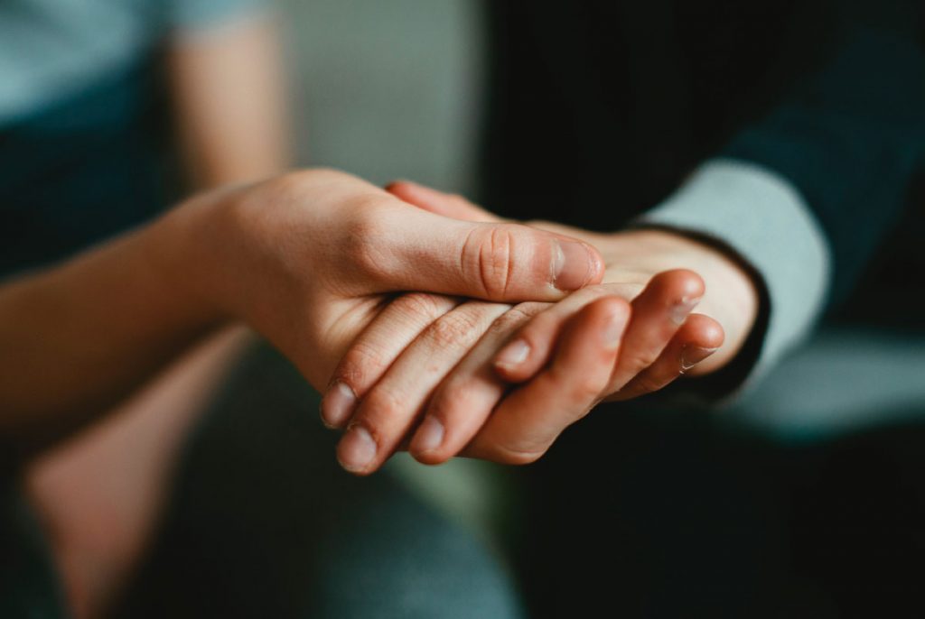 A person's hand held in the palm of another person's hand.