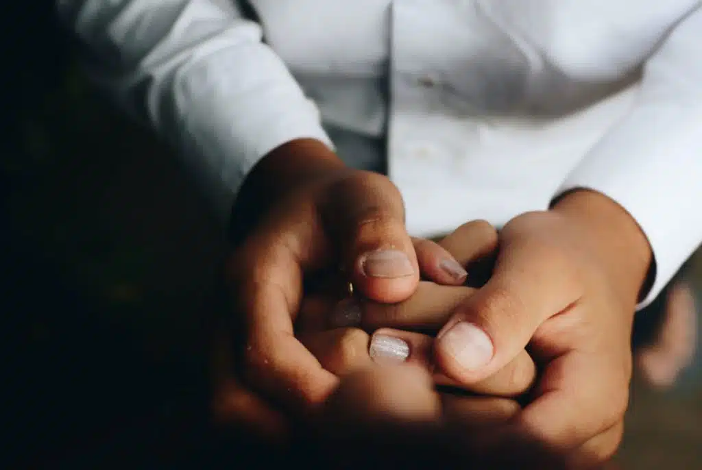 A person holding another person's hands between their own.