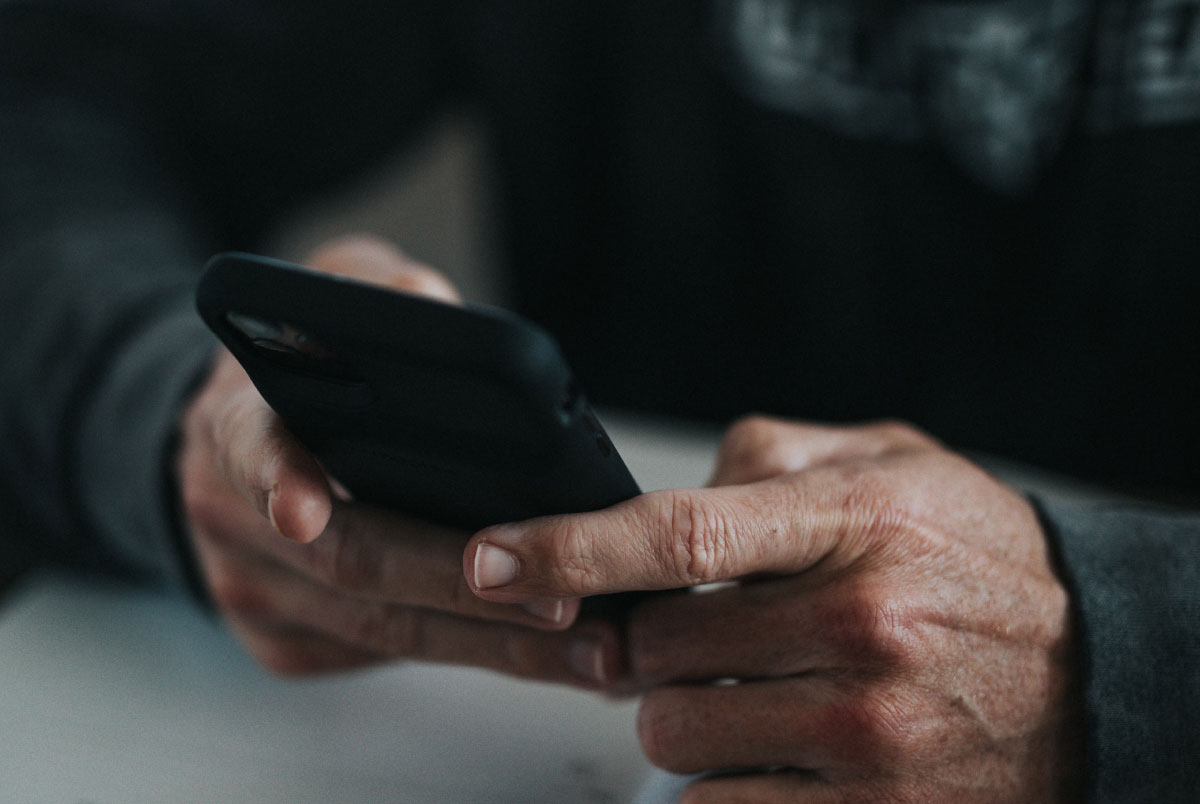 Hands using mobile device to navigate technology and relationships.