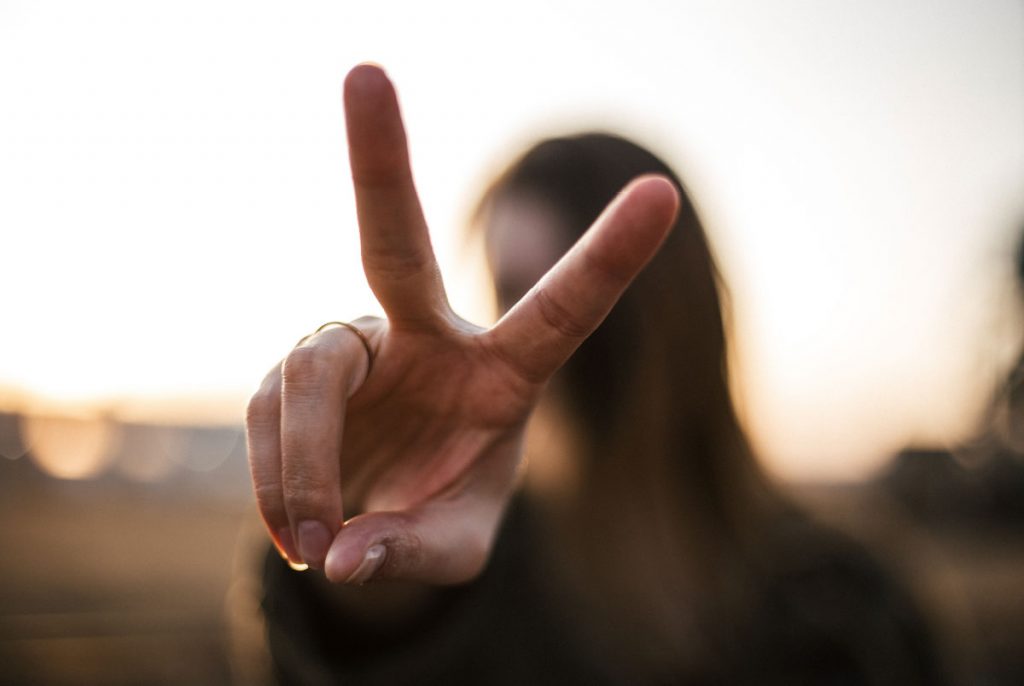 A person holding out their hand in a peace sign.
