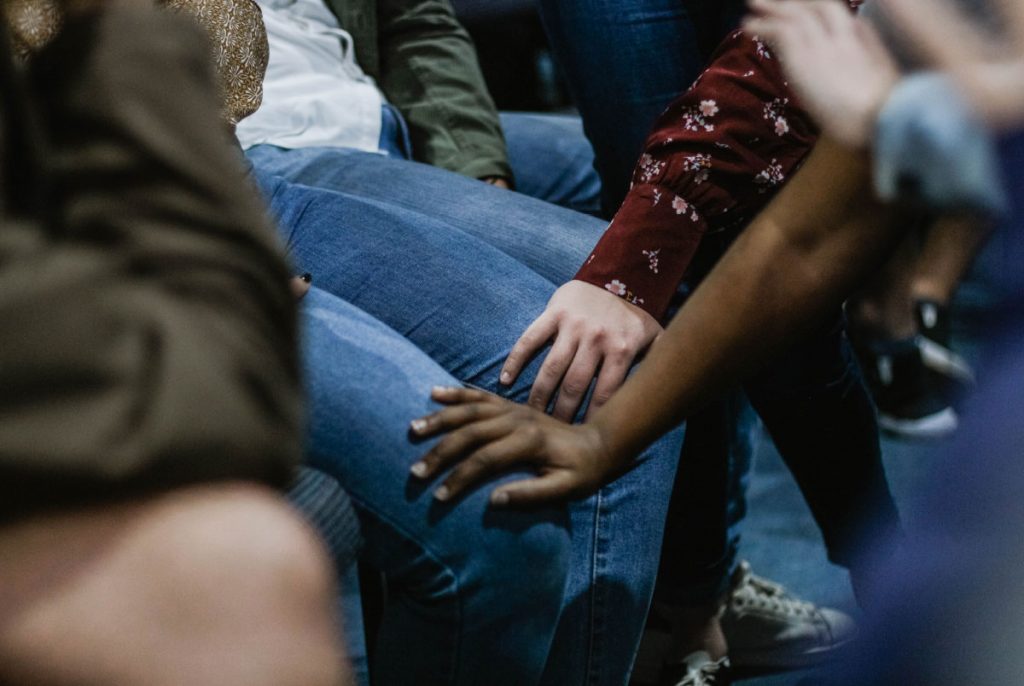 Two children's hands placed on a person's knees.