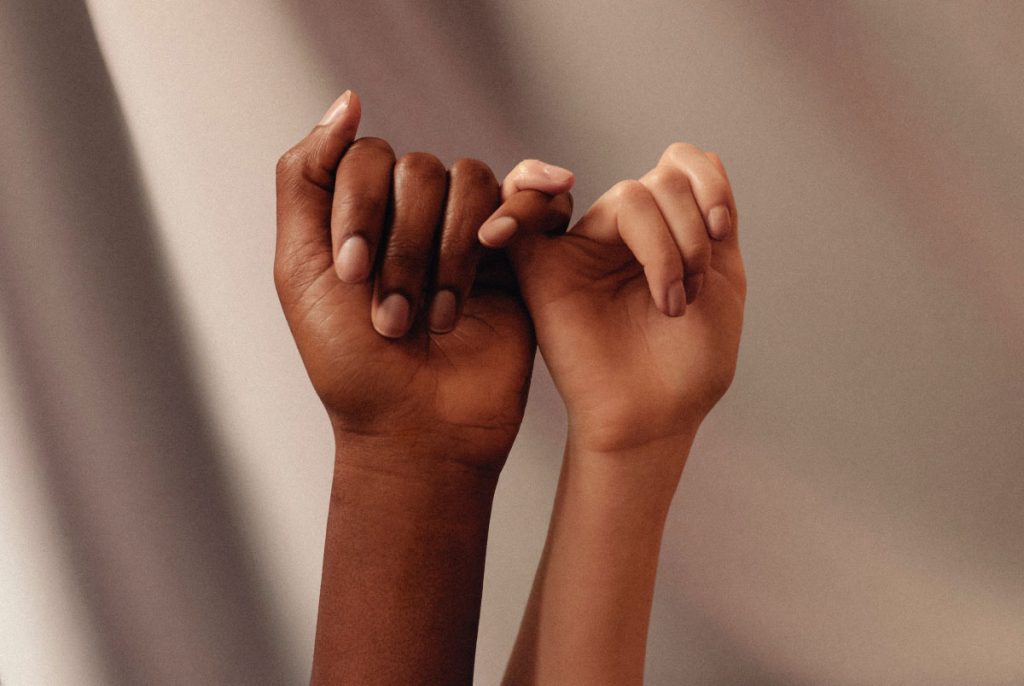Two people's hands with linked little fingers.