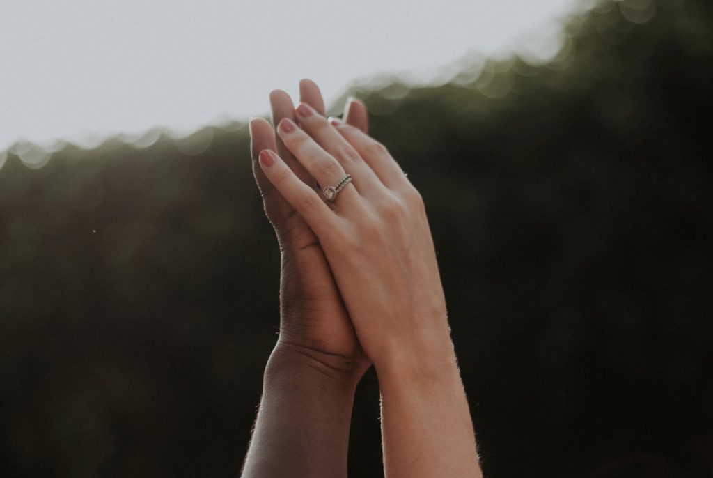 Two people's palms touching, reaching upward.
