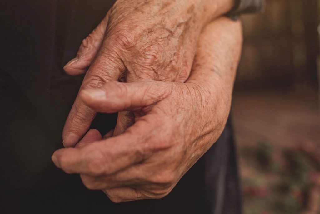 Two elderly hands holding one another.