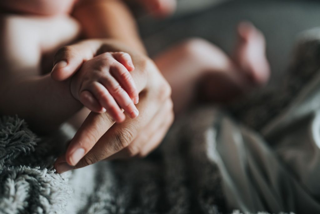 An adult holding a baby's hand.