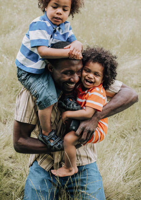 Man juggling two little boys in his arms.