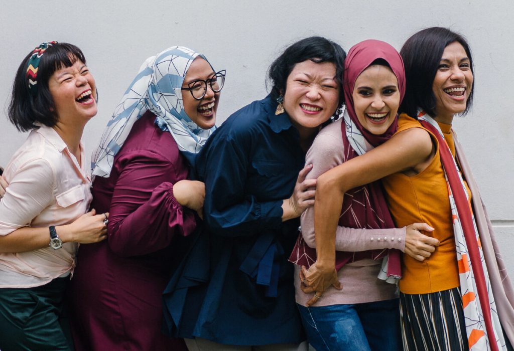 Women in a line laughing.