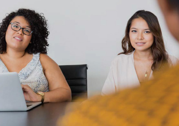 Two women talking to colleague in office.