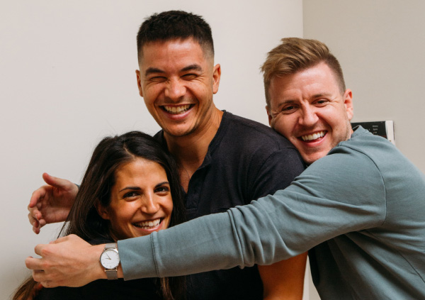 Group hug with three people smiling.