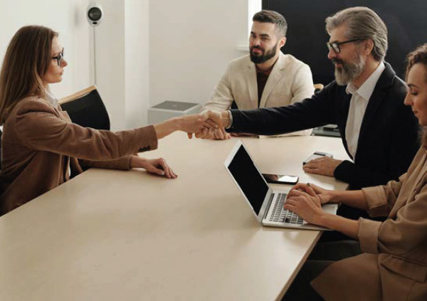 People in office shaking hands over a table.