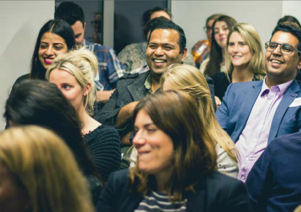 Group of people laughing as they watch a talk.