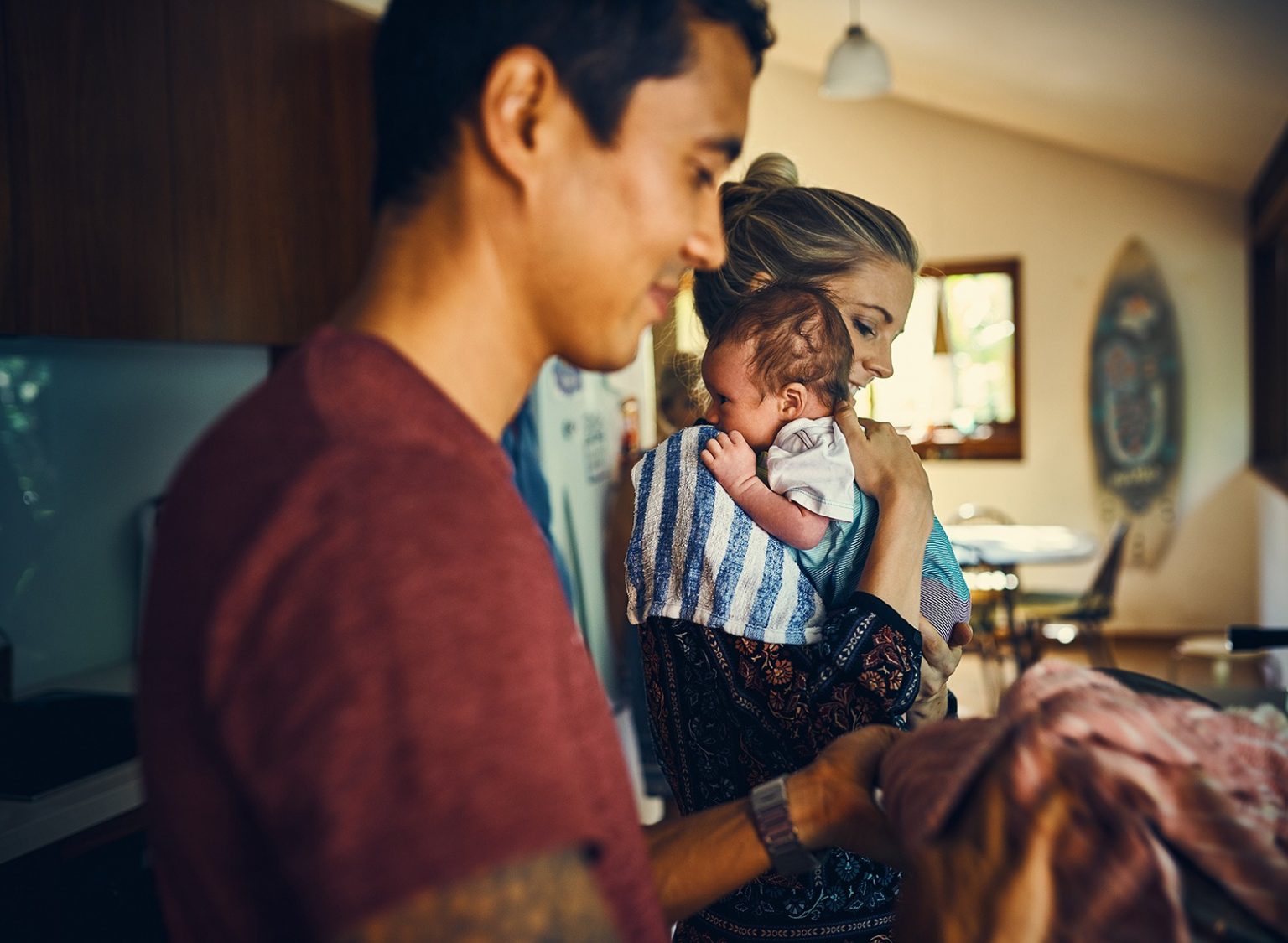 Woman holding baby while man holds tea towel