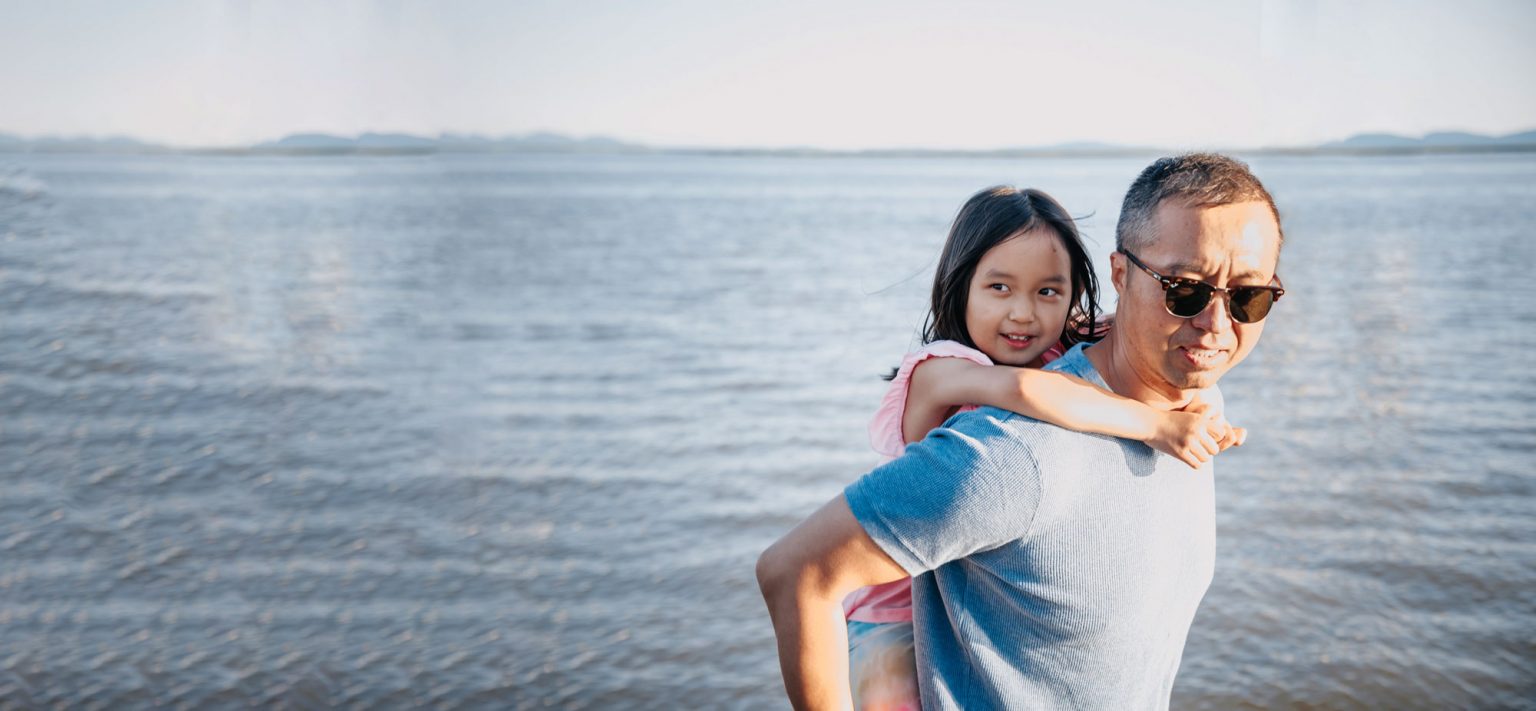 Child piggy backing on father overlooking a lake