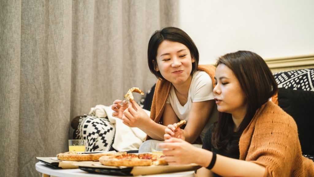 two women eating pizza together