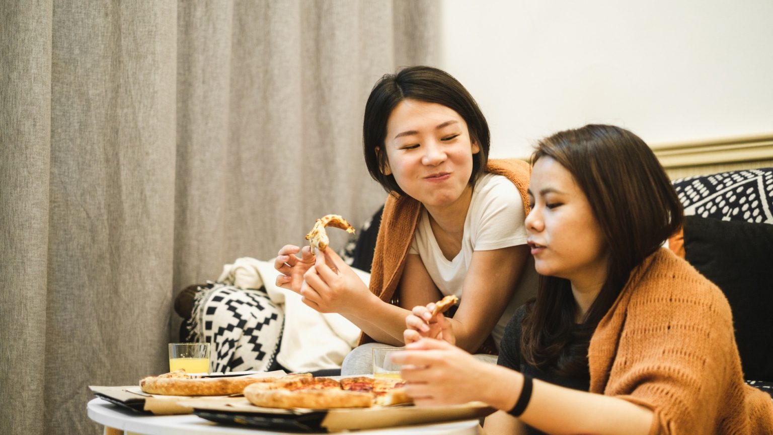 two women eating pizza together