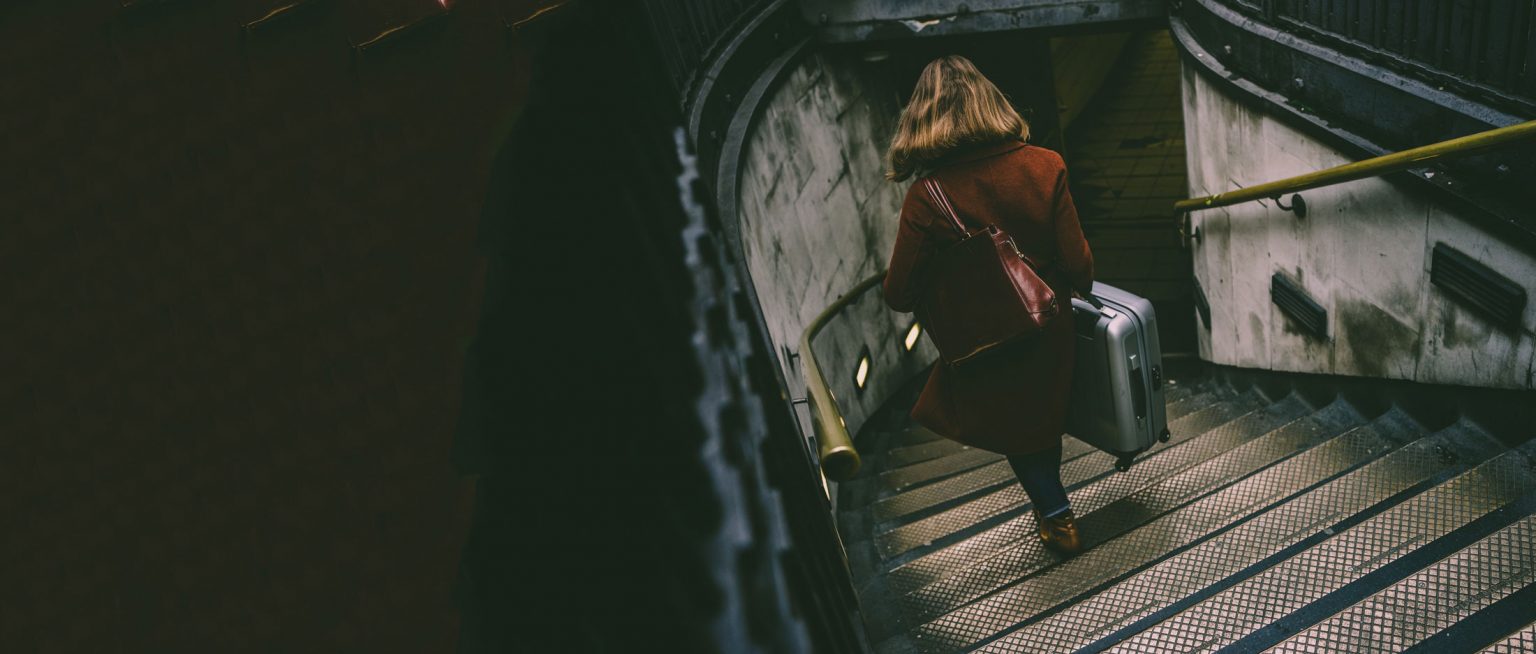 Woman holding suitcase walking down stairs