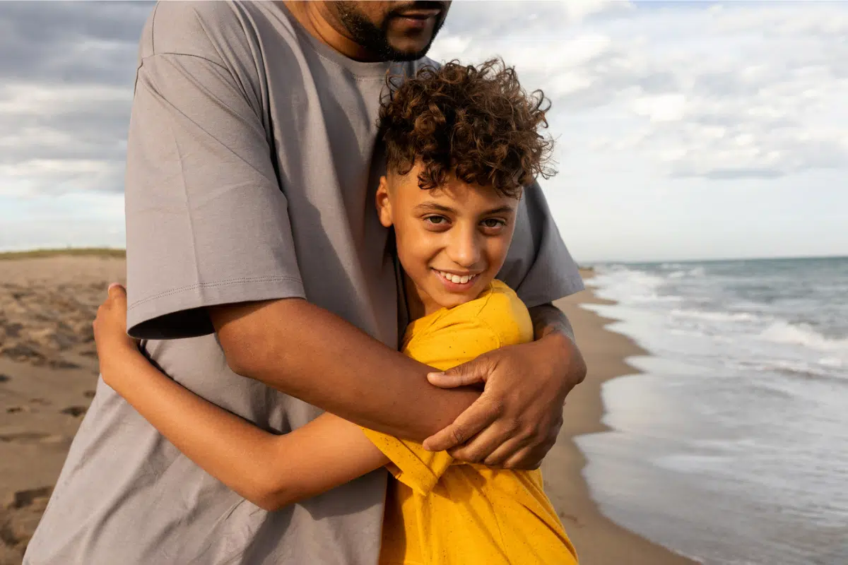 son hugging dad on beach