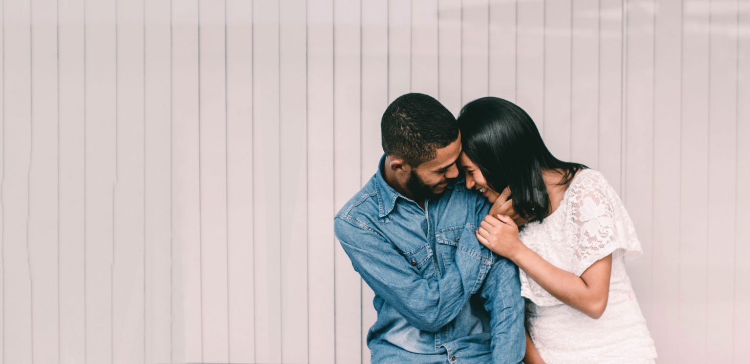 man and woman snuggling, man with hand on woman's face