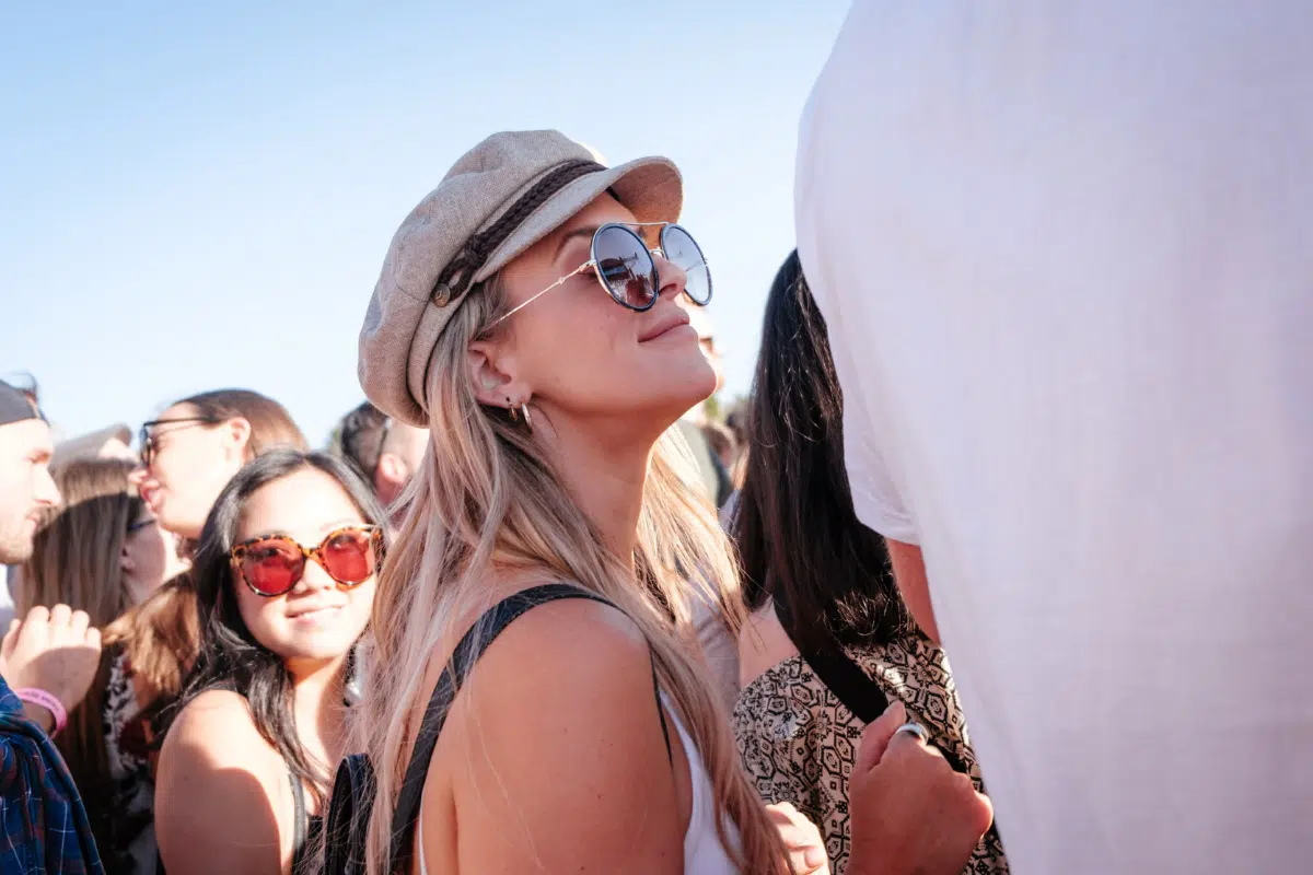 woman at a festival in a hat and sunglasses staring at man