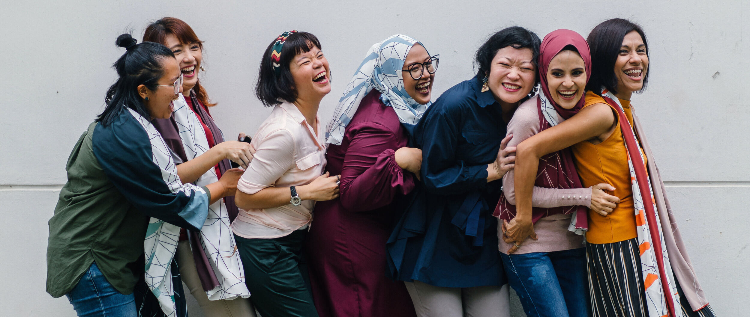 Women standing in conga-line laughing.