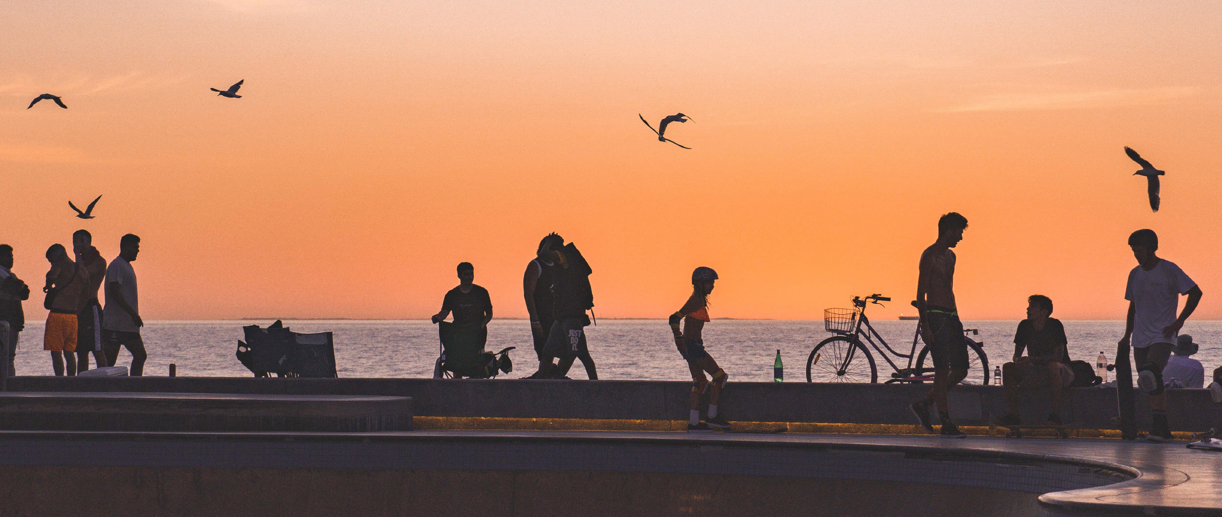 Silhouettes of people beside the ocean.