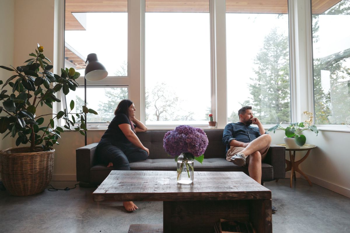 Couple sitting apart on a sofa with one turned away from the other