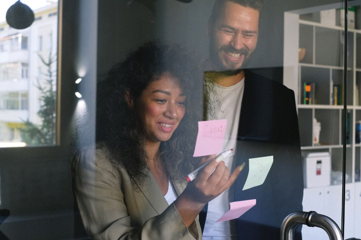 Colleagues putting post-it notes onto board and smiling