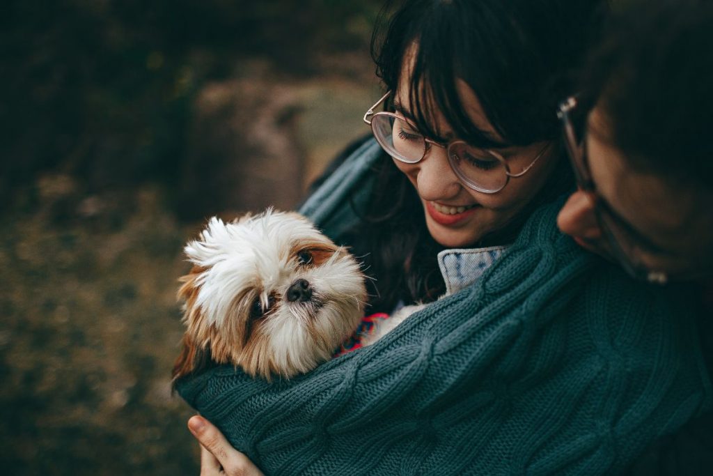 Young couple holding their dog and looking at it lovingly