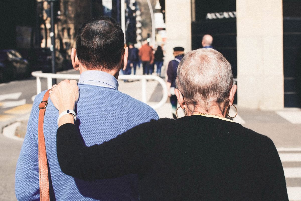 Back of the heads of two friends walking down the street, with arm around one another