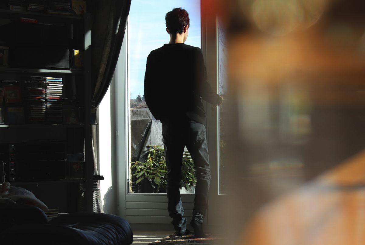 Young man looking out from his house into the garden