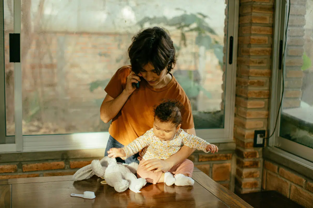 mum holding baby on counter playing with bunny toy