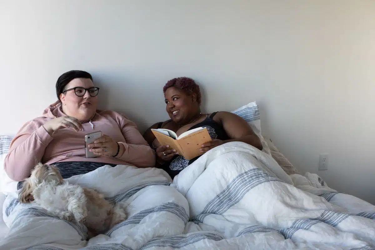 Couple lying in bed talking and reading a book