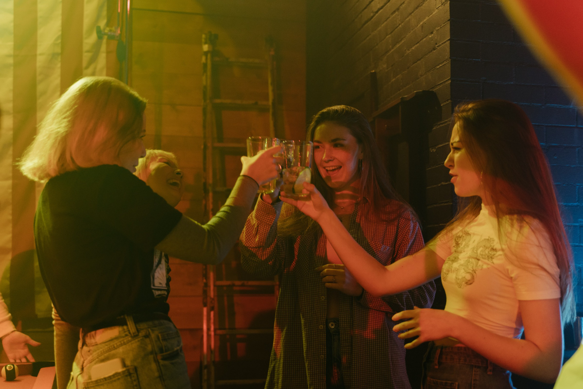 Group of 4 friends cheers-ing with drinks in a bar.