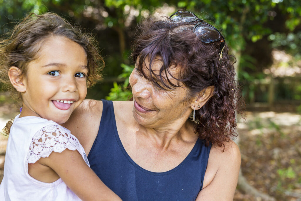 Australian Aboriginal woman giving child a hug in the park