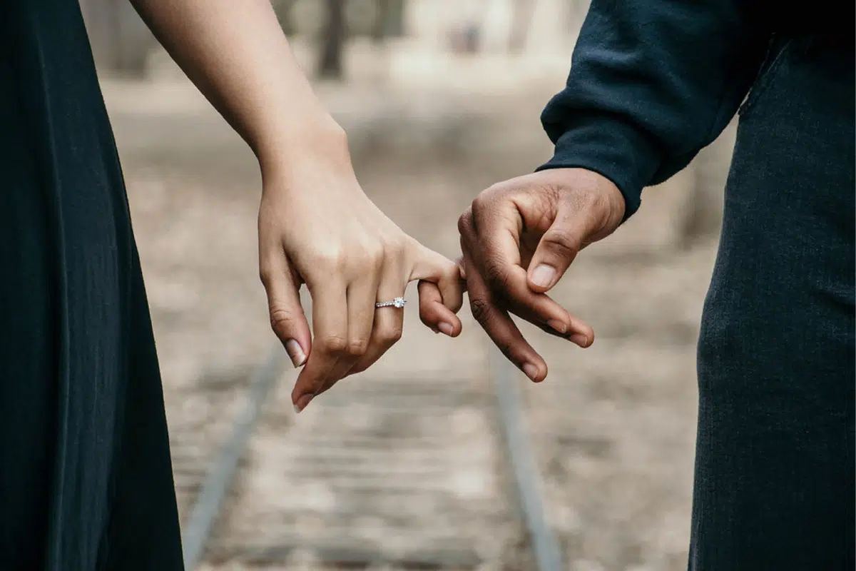 two people holding hands on train track