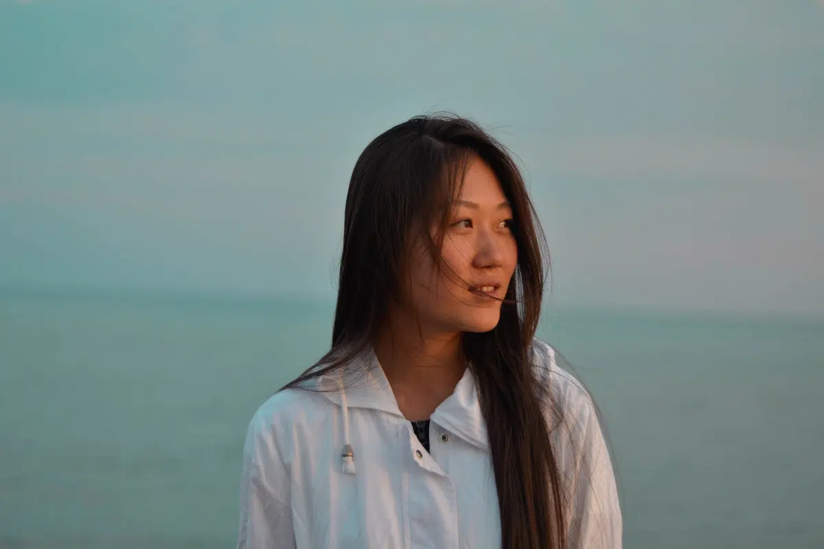 asian woman looking to the side in front of ocean