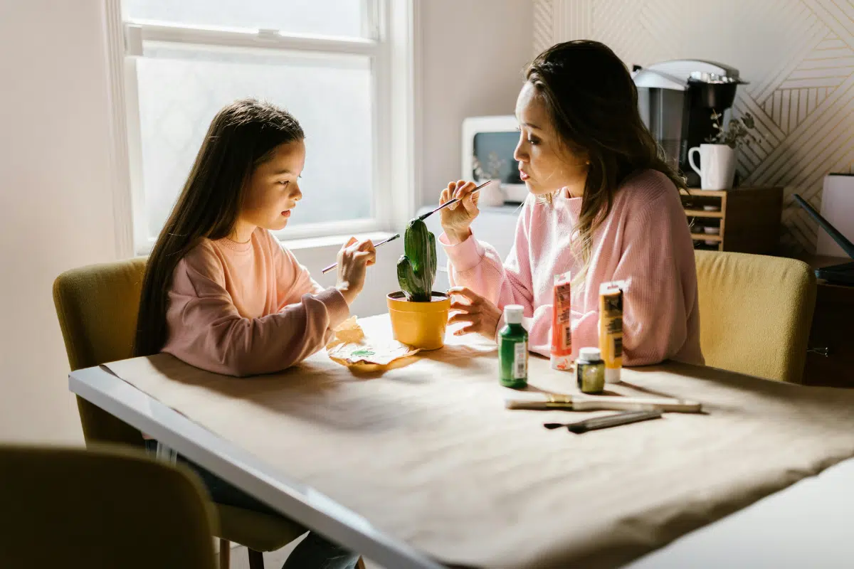 mother and young daughter painting at table