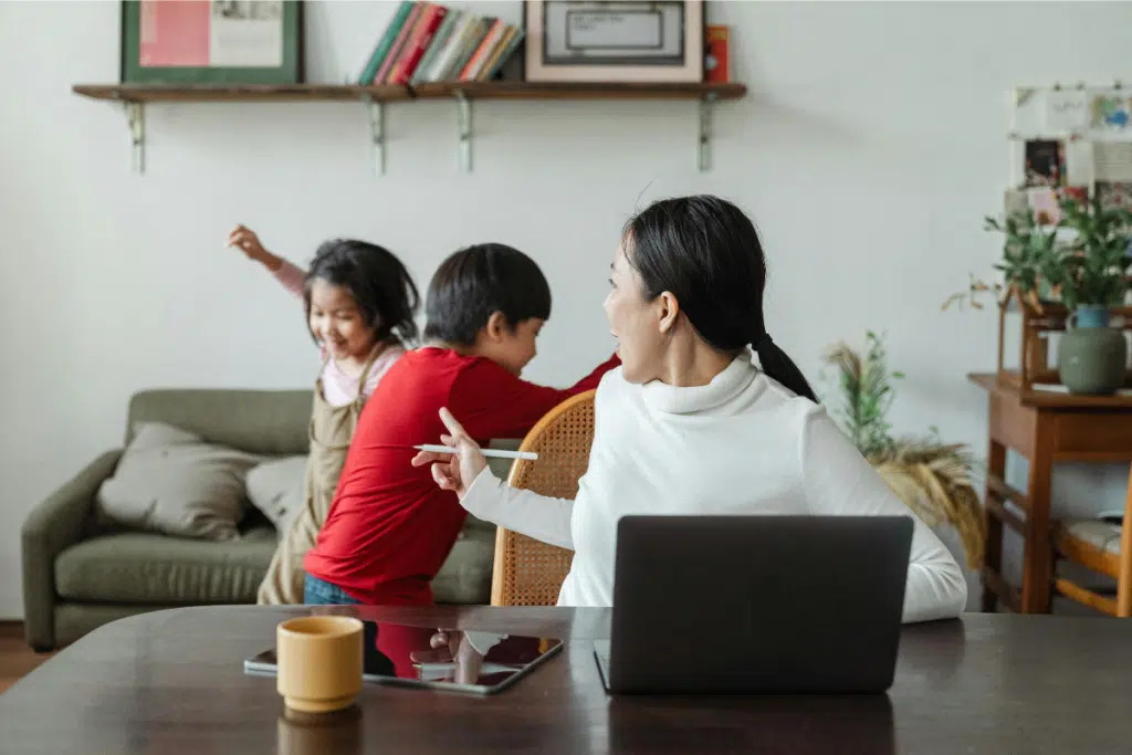 mum working at desk and two children playing