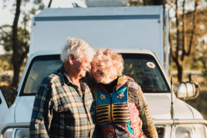 older couple smiling at each other in front of car campervan